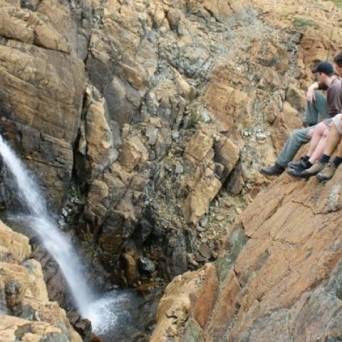 a man sitting on a rock next to a waterfall