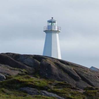 a rocky island in the middle of a body of water with Pigeon Point Lighthouse in the background