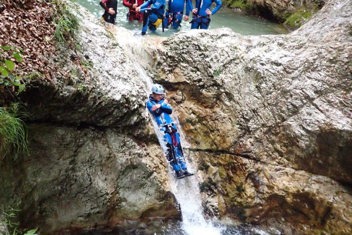 a group of people on a rock next to a waterfall