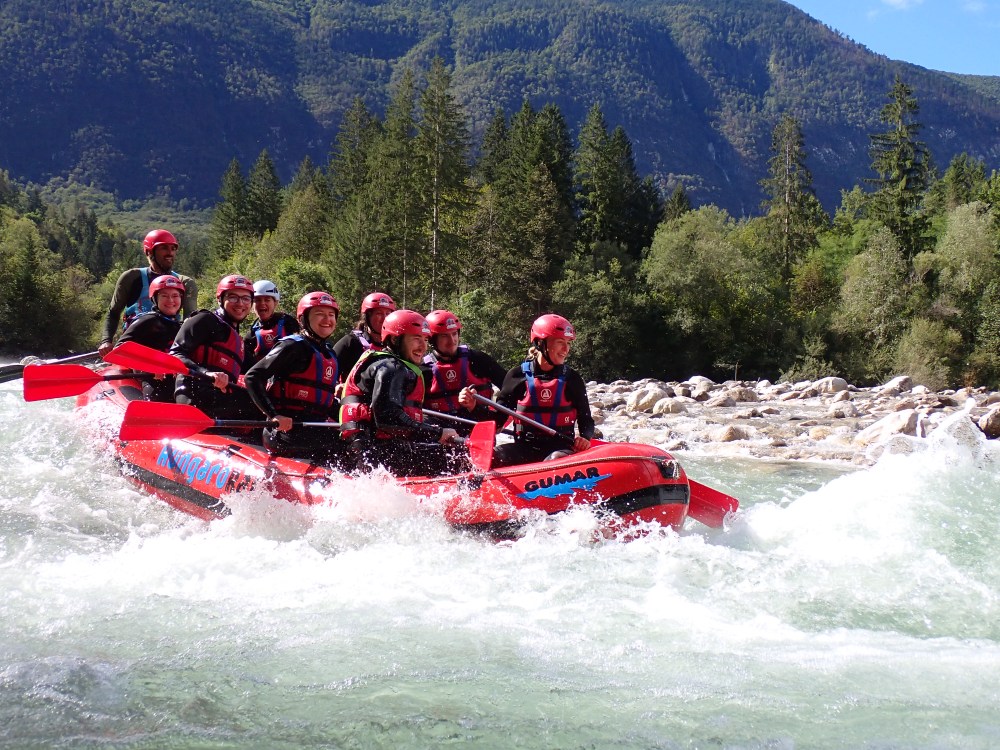 HungaroRaft guests whitewater rafting on the emerald Soča River, surrounded by Julian Alps mountains.